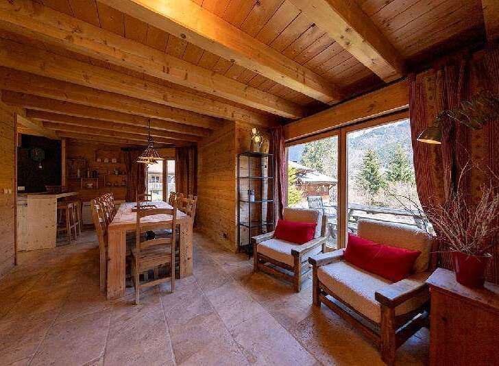 This stunning chalet boasts a spacious open-plan living area with large windows offering breathtaking mountain views.
