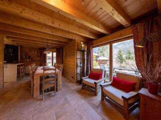 This stunning chalet boasts a spacious open-plan living area with large windows offering breathtaking mountain views.