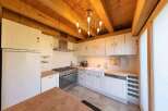 This stunning kitchen boasts a charming wooden beam ceiling and a beautiful chandelier, creating a warm and inviting atmosphere.