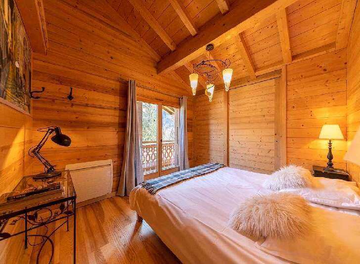 Cozy wooden cabin bedroom with a comfortable double bed, soft pillows, and warm lighting.