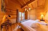 Cozy wooden cabin bedroom with a comfortable double bed, soft pillows, and warm lighting.