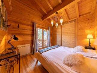 Cozy wooden cabin bedroom with a comfortable double bed, soft pillows, and warm lighting.