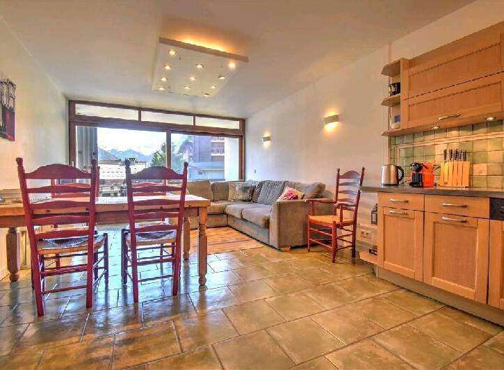 This charming apartment boasts a spacious living area with large windows offering stunning mountain views, a fully equipped kitchen, and a cozy dining area perfect for family meals.