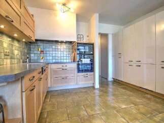 This stunning kitchen boasts modern light wood cabinetry, complemented by sleek countertops and a stylish backsplash.