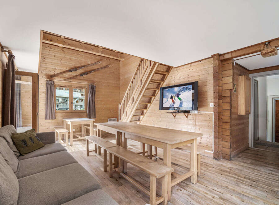 Cozy chalet living room with rustic wood walls and floors, featuring a large dining table perfect for family gatherings.