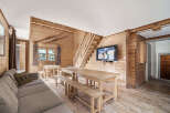 Cozy chalet living room with rustic wood walls and floors, featuring a large dining table perfect for family gatherings.