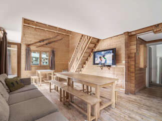 Cozy chalet living room with rustic wood walls and floors, featuring a large dining table perfect for family gatherings.