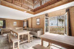 This stunning chalet boasts a spacious open-plan living area with multiple wooden dining tables perfect for large groups.