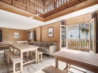 This stunning chalet boasts a spacious open-plan living area with multiple wooden dining tables perfect for large groups.