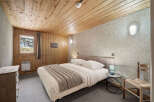 Cozy chalet bedroom with wood paneling and a comfortable double bed.