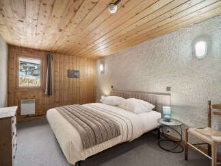 Cozy chalet bedroom with wood paneling and a comfortable double bed.