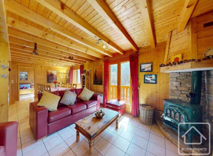 This stunning chalet boasts a spacious open-plan living area with exposed wooden beams, a cozy fireplace, and large windows offering breathtaking views.