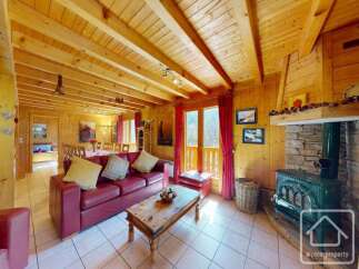 This stunning chalet boasts a spacious open-plan living area with exposed wooden beams, a cozy fireplace, and large windows offering breathtaking views.