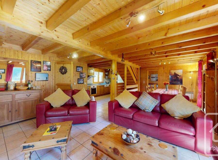 This stunning chalet boasts a spacious open-plan living area with exposed wooden beams, creating a warm and inviting atmosphere.