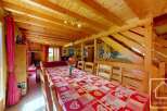 This charming chalet boasts a spacious dining area with a large wooden table perfect for family gatherings, complemented by a warm and inviting living room with a cozy fireplace.