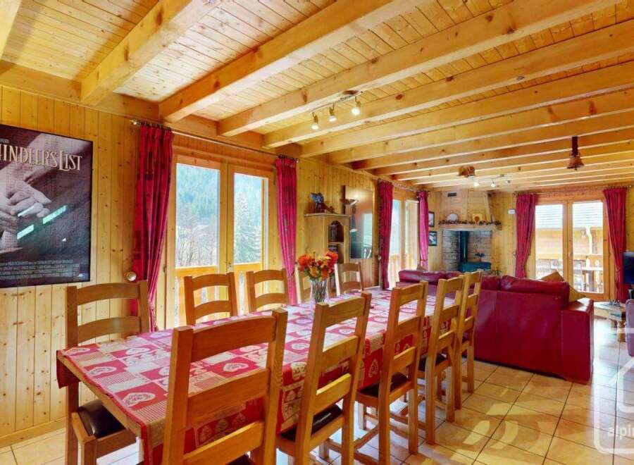 This stunning chalet boasts a spacious dining area with a large wooden table perfect for family gatherings, complemented by a cozy living room featuring a fireplace and comfortable seating.