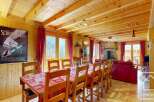 This stunning chalet boasts a spacious dining area with a large wooden table perfect for family gatherings, complemented by a cozy living room featuring a fireplace and comfortable seating.