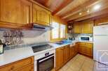 This charming kitchen boasts a rustic wooden design with modern appliances, including a built-in oven and hob, microwave, and refrigerator.
