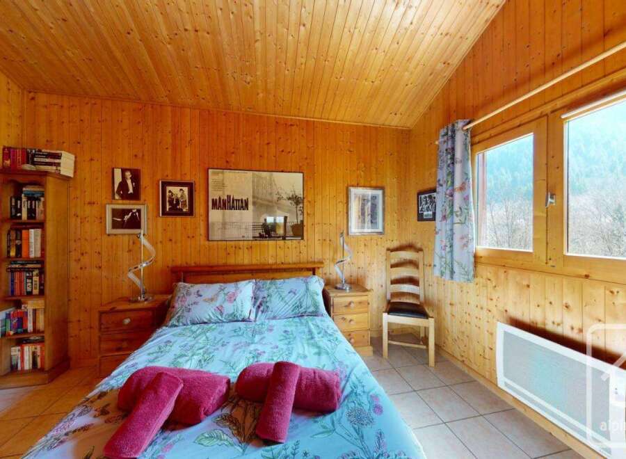 Cozy chalet bedroom with wooden walls and a view of the mountains.