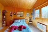 Cozy chalet bedroom with wooden walls and a view of the mountains.