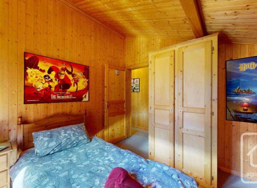 Cozy chalet bedroom with wooden walls and built-in wardrobe.