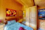 Cozy chalet bedroom with wooden walls and built-in wardrobe.