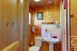 Cozy chalet bathroom with wood paneling, featuring a toilet, sink, and shower.