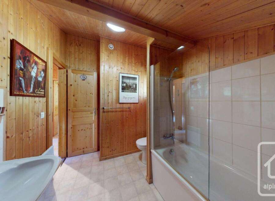 This charming bathroom boasts a combination of wood paneling and tiled walls, creating a warm and inviting atmosphere.