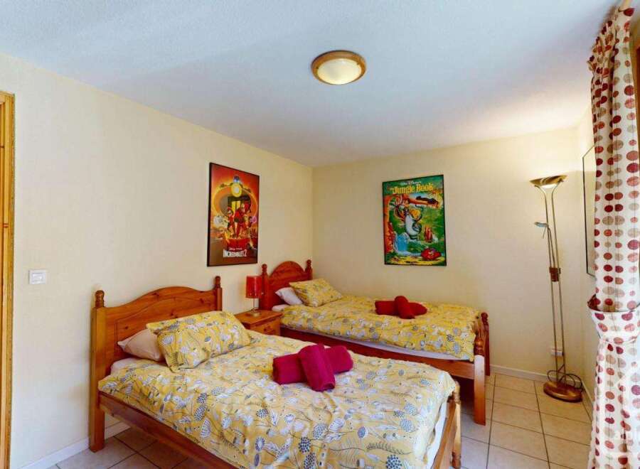 Cozy twin bedroom with bright yellow bedding, featuring two single beds and charming Disney-themed posters.