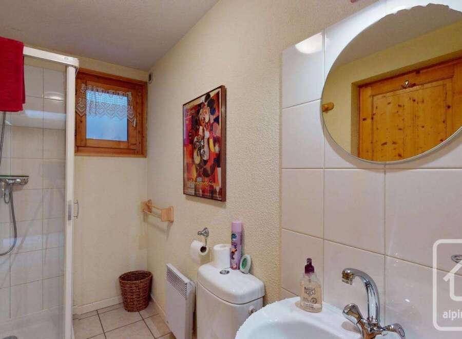 This charming bathroom boasts a walk-in shower, toilet, and sink, complete with a stylish mirror and ample storage.