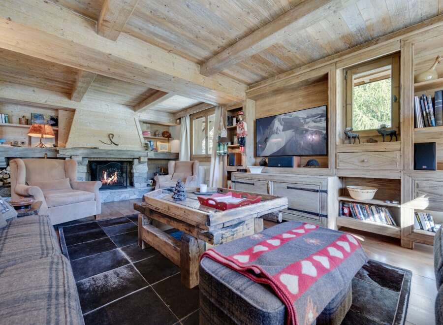 This stunning chalet boasts a spacious living area with exposed wooden beams, a cozy fireplace, and large windows offering breathtaking views.
