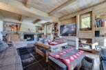 This stunning chalet boasts a spacious living area with exposed wooden beams, a cozy fireplace, and large windows offering breathtaking views.