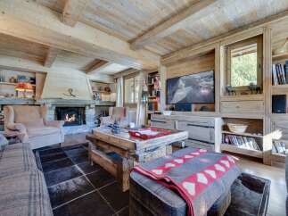 This stunning chalet boasts a spacious living area with exposed wooden beams, a cozy fireplace, and large windows offering breathtaking views.
