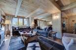 This stunning chalet boasts a spacious living area with exposed wooden beams and a cozy fireplace, creating a warm and inviting atmosphere.