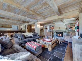 This stunning chalet boasts a spacious living area with exposed wooden beams and a cozy fireplace, creating a warm and inviting atmosphere.