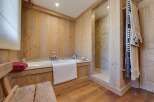 This luxurious bathroom boasts a rustic-chic design with wood paneling, a freestanding bathtub, and a separate shower.