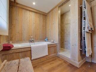 This luxurious bathroom boasts a rustic-chic design with wood paneling, a freestanding bathtub, and a separate shower.