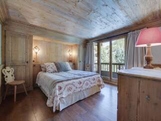 This charming bedroom boasts a rustic wooden interior with exposed beams and wood paneling, creating a cozy and inviting atmosphere.