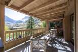 This stunning chalet boasts a spacious wooden deck with breathtaking mountain views.