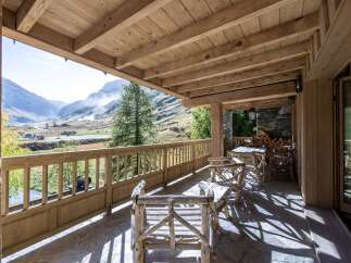 This stunning chalet boasts a spacious wooden deck with breathtaking mountain views.