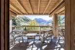 Mountain view chalet with wooden deck and rustic furniture.