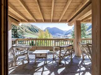 Mountain view chalet with wooden deck and rustic furniture.