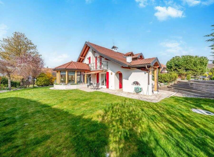 Discover this charming property featuring a spacious green lawn perfect for outdoor activities and a beautiful white house with a red-tiled roof.