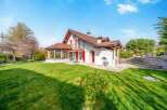 Discover this charming property featuring a spacious green lawn perfect for outdoor activities and a beautiful white house with a red-tiled roof.