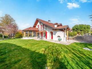 Discover this charming property featuring a spacious green lawn perfect for outdoor activities and a beautiful white house with a red-tiled roof.