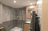 This stunning bathroom boasts modern gray tile, a spacious walk-in shower, and a sleek wooden vanity.