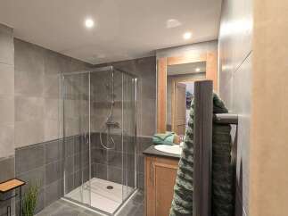 This stunning bathroom boasts modern gray tile, a spacious walk-in shower, and a sleek wooden vanity.