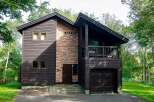 This stunning two-story home boasts a unique architectural design, featuring a blend of dark wood siding and a striking stone accent wall.