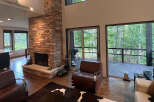 This stunning home boasts an open floor plan with hardwood floors, a cozy stone fireplace, and large windows offering breathtaking views of the surrounding forest.