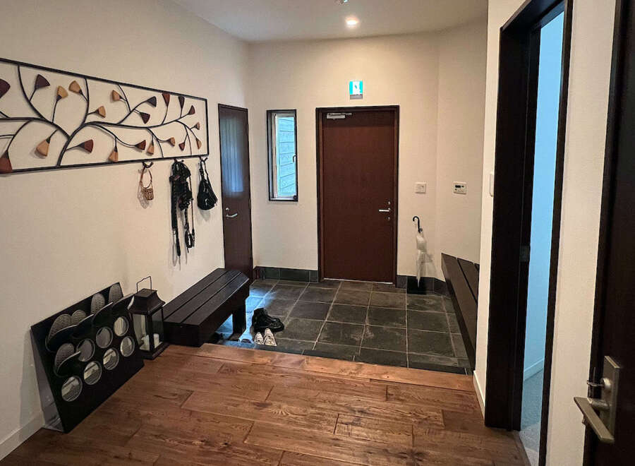 This charming entryway boasts a unique metal wall art piece, a convenient bench for seating, and ample storage for shoes and outerwear.
